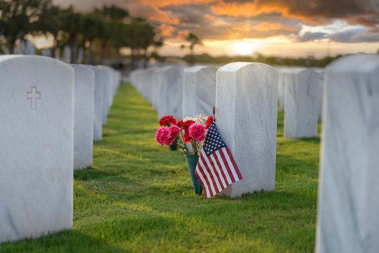 Military cemetrary with a flag and flowers.