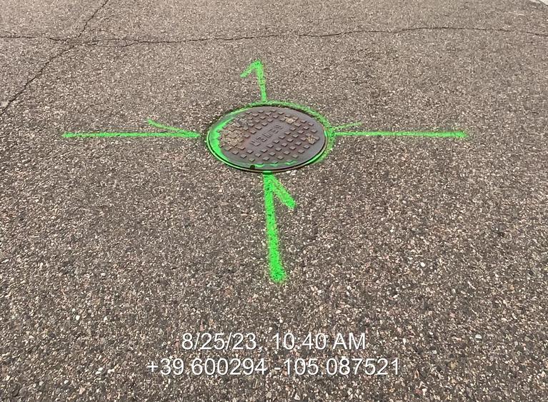 Sewer locates around a manhole in the street. 